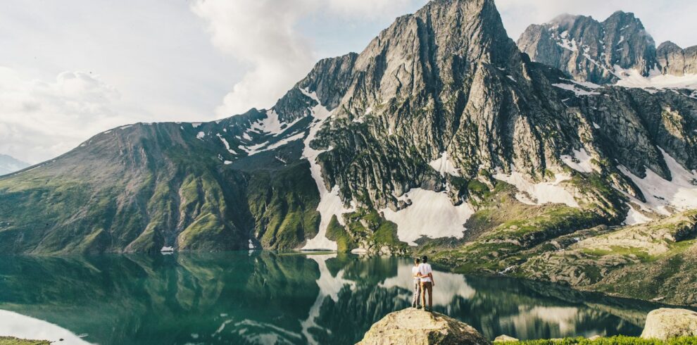 person standing on rock near lake and mountain range