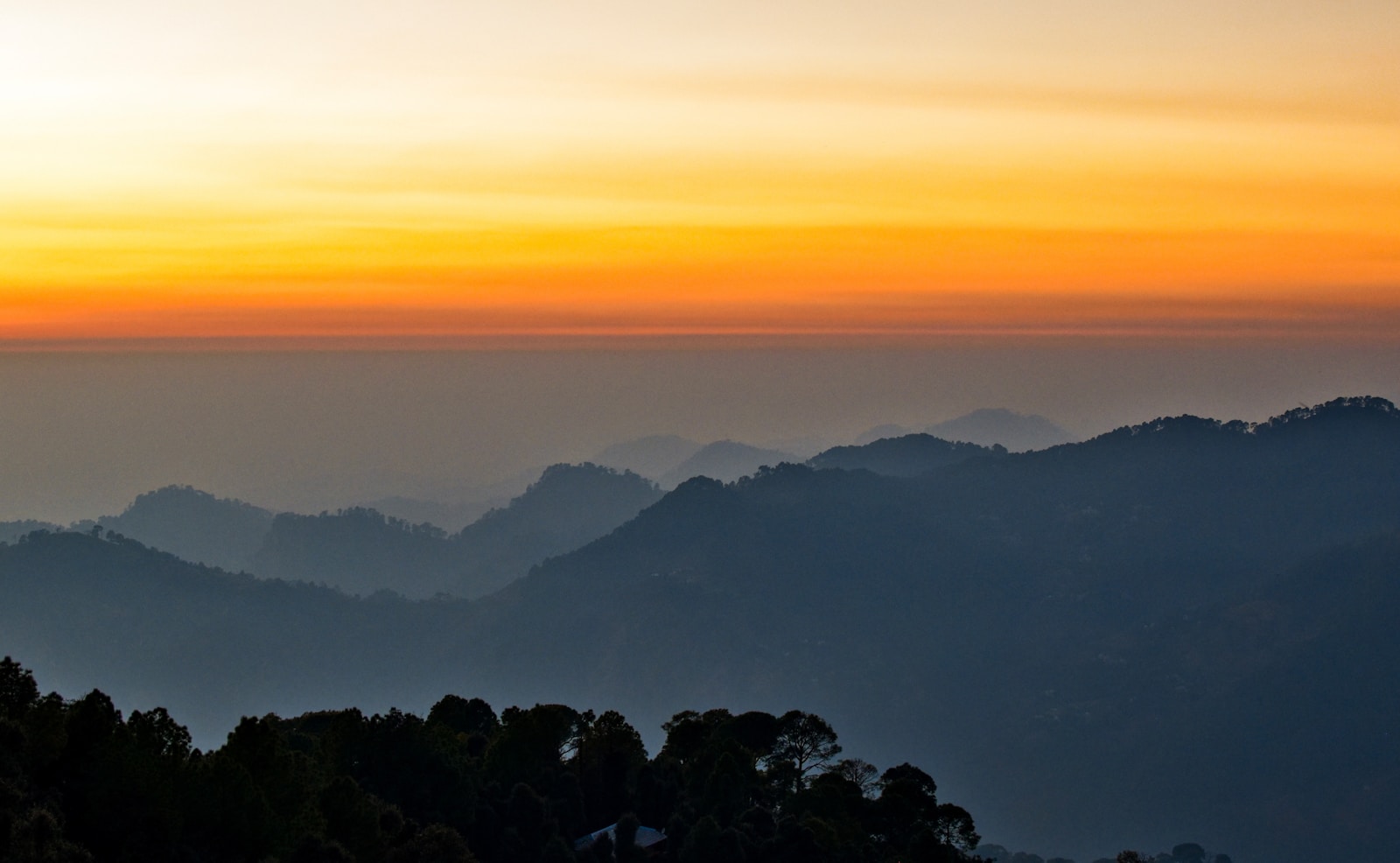 the sun is setting over a mountain range