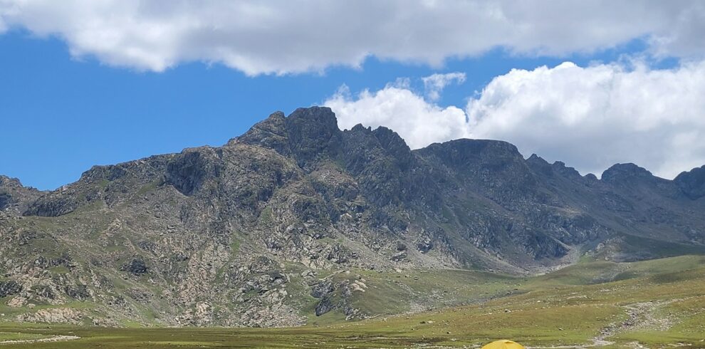 a tent in a field with mountains in the background