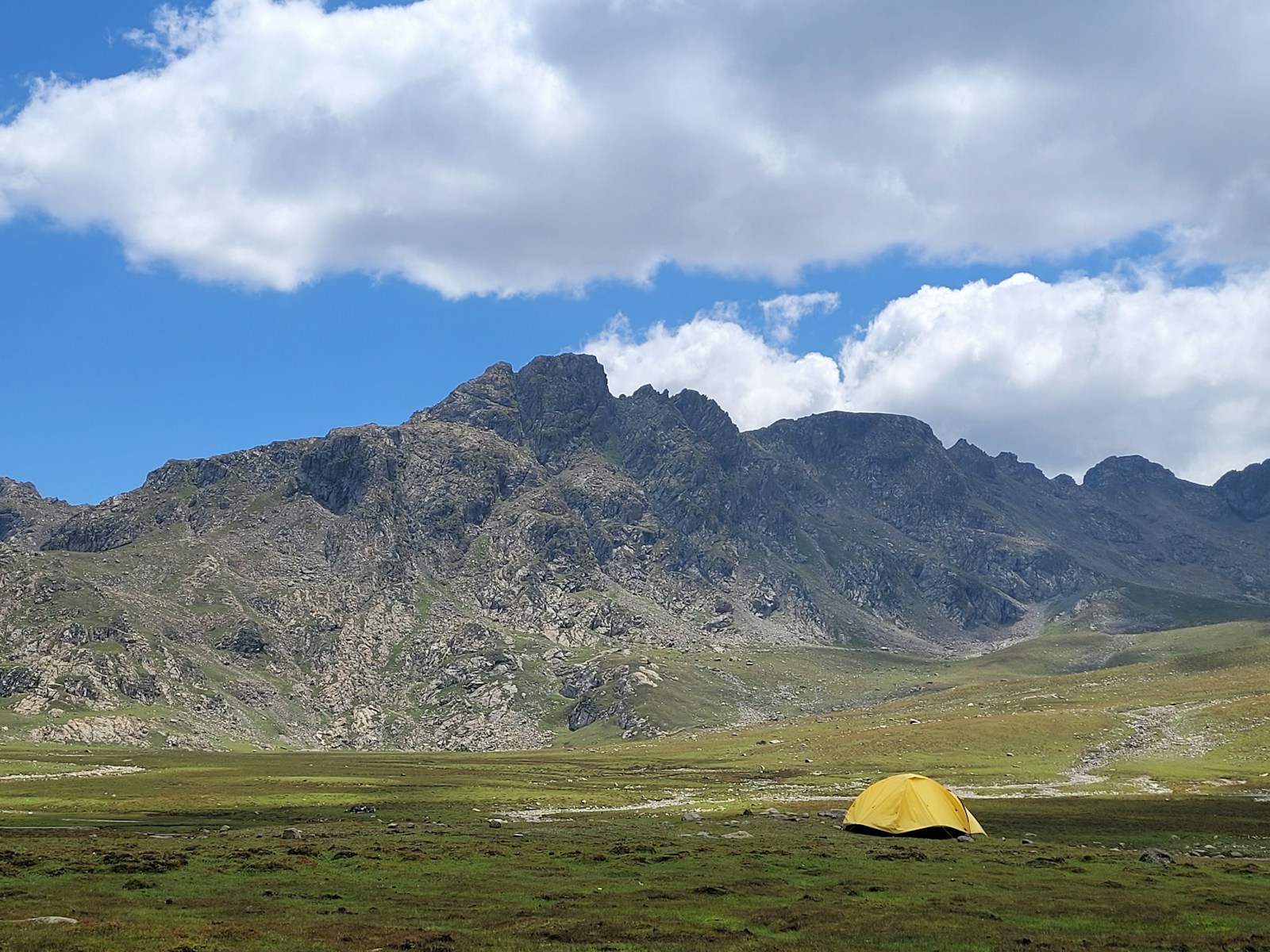 a tent in a field with mountains in the background